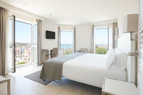 a white bedroom with a large bed and large windows at Gran Hotel Suances in Suances