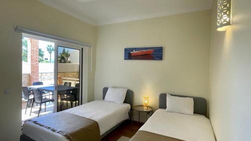twee bedden in een kamer met een tafel en een raam bij Oura Oasis B by Check-in Portugal in Albufeira