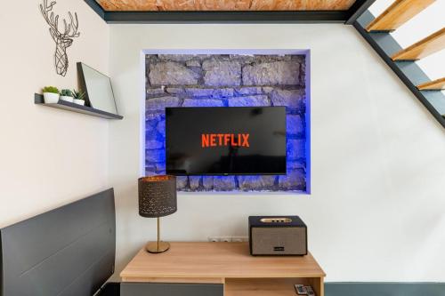 a living room with a tv on a wall at Le Charmant Hypercentre tram design in Saint-Étienne