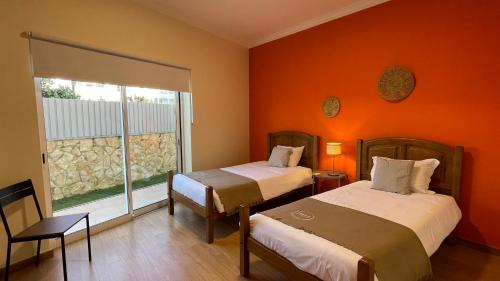 2 camas en una habitación con paredes de color naranja y ventana en Oura Oasis C by Check-in Portugal en Albufeira