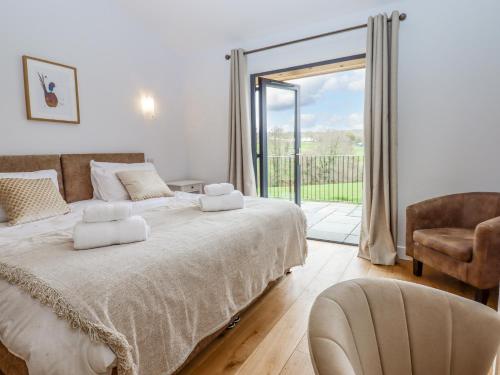 a bedroom with a bed and a chair and a window at Woodpecker Lodge in Cullompton