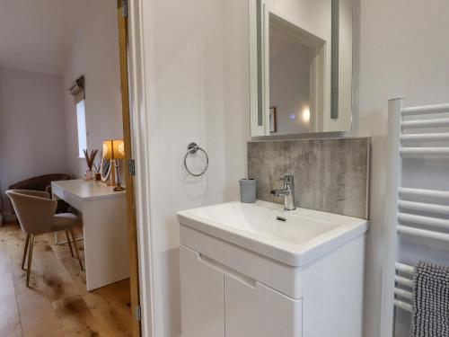 a white bathroom with a sink and a mirror at Woodpecker Lodge in Cullompton
