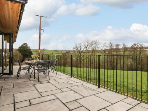 a patio with a table and chairs and a fence at Woodpecker Lodge in Cullompton