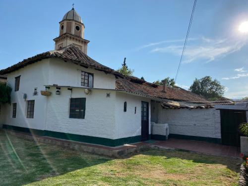 ein weißes Gebäude mit einem Uhrturm darüber in der Unterkunft Cabaña con excelente ubicación y zona verde. in Iza