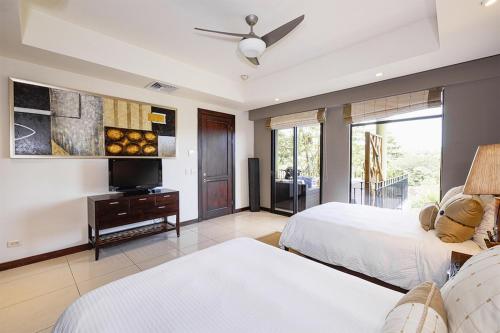 1 dormitorio con 2 camas y TV de pantalla plana en Carao T5-3 Luxury Apartment - Reserva Conchal, en Playa Conchal