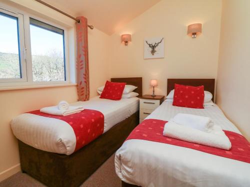 two beds in a small room with a window at Chalet Log Cabin C11 in Ilfracombe
