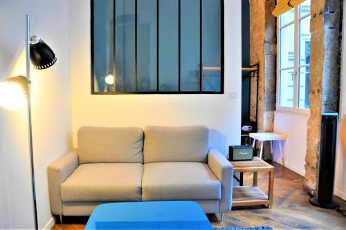 uma sala de estar com um sofá e uma mesa em Le Blue - hypercentre - Presque île em Lyon