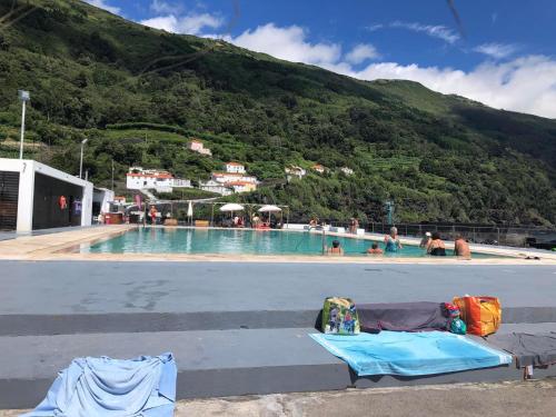 a swimming pool with people in the water and a mountain at Casa da Bicuda in Ribeiras