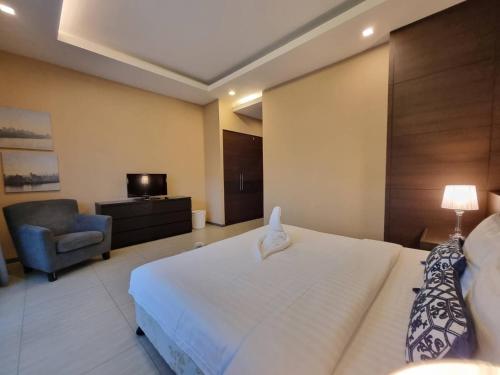 a bedroom with a large white bed and a chair at Midas Pool Villa in Jomtien Beach
