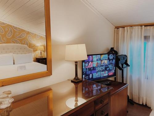 a bedroom with a bed and a desk with a television at Five Seasons Pension in Nafplio