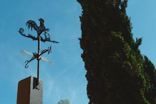 a weather vane with a chicken on it next to a tree at 23Apartments in La Spezia