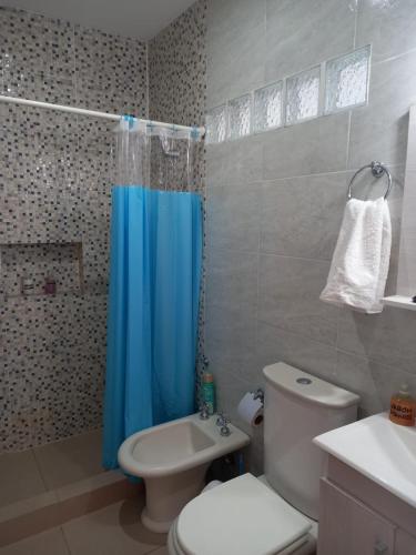 a bathroom with a toilet and a blue shower curtain at Complejo TuLuz - Dpto 1 dormitorio con cochera y Monoambiente, con cochera opcional en Tolosa, La Plata, in Tolosa