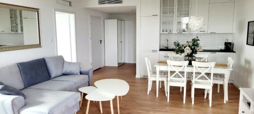 a living room with a couch and a table and chairs at PINEA Apartments Pobierowo z niesamowitym widokiem na morze oraz jacuzzi w wybranych apartamentach in Pobierowo