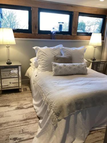 a bedroom with a white bed with two windows at Harcombe Barn near Bristol in Bristol