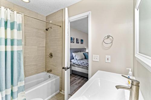 a bathroom with a bath tub and a sink at Bay Street Bliss in Gulf Breeze