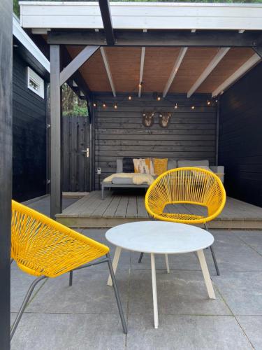 twee gele stoelen en een tafel op een patio bij Sfeervol guesthouse, privé tuin en free parking in Rotterdam