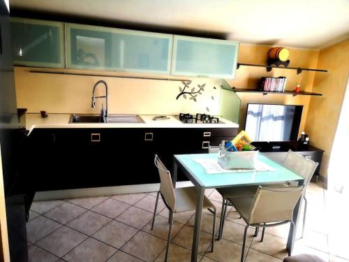 cocina con mesa, sillas y fregadero en Casa in mansarda con terrazza, en Caronno Pertusella