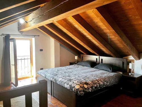 sypialnia z dużym łóżkiem i drewnianym sufitem w obiekcie Agriturismo Cascina Clavarezza w mieście Valbravenna