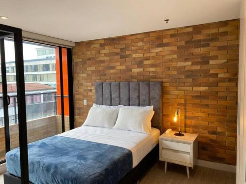 1 dormitorio con 1 cama con pared de ladrillo en Apartamento 512 academia, en Bogotá
