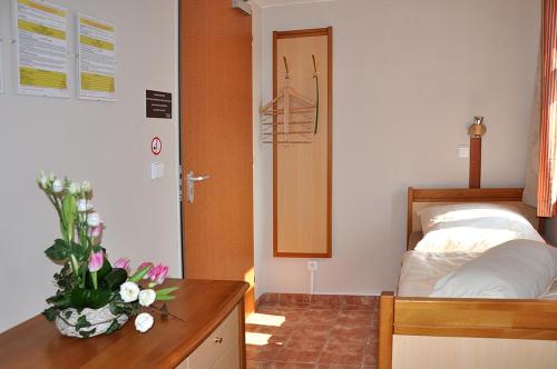 a bedroom with a bed and a vase of flowers on a desk at Apartmány Rosalka in Stará Oleška