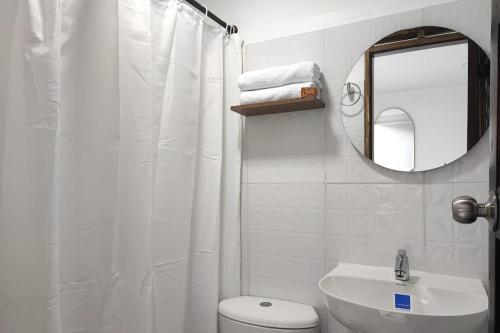 La salle de bains blanche est pourvue de toilettes et d'un miroir. dans l'établissement Ayenda Hotel Helenas, à Ríohacha