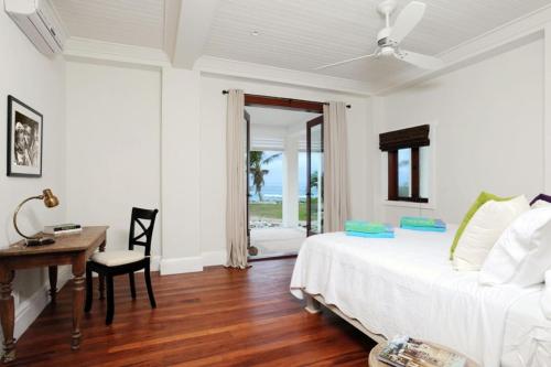 a bedroom with a bed and a desk and a window at Alfred House home in Governorʼs Harbour