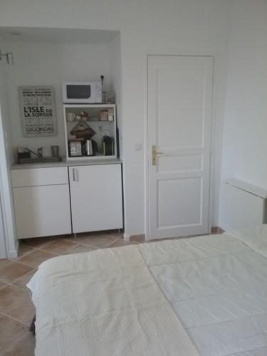 a room with a kitchen with a refrigerator and a door at UNE CHAMBRE EN VILLE in L'Isle-sur-la-Sorgue