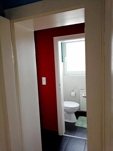 a bathroom with a red door and a toilet at Shiraz-Home das Ferienhaus in Holzminden, 120qm Privatsphäre für ungestörte Erholung in Holzminden