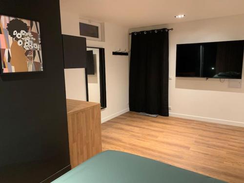 a living room with black curtains and a wooden floor at Appartement avec jacuzzi dans la chambre et piscine aux beaux jours in Vaudancourt