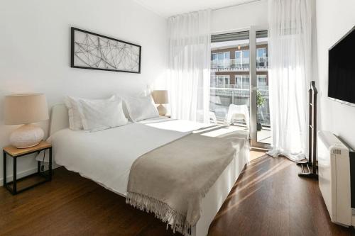 um quarto branco com uma cama grande e uma janela em Lisbon Metro & Pool Apartment em Lisboa