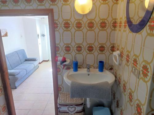 a bathroom with a sink and a blue couch at Casa vacanze Marinella in Santo Stefano al Mare
