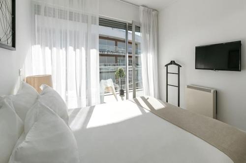 a white bedroom with a bed and a television at Lisbon Metro Apartment in Lisbon