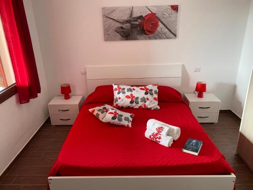 ein Schlafzimmer mit einem roten Bett mit roten Laken und Kissen in der Unterkunft Villetta Capo Comino 500 m DAL MARE in Siniscola