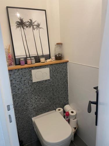 La salle de bains est pourvue de toilettes et d'une photo de palmiers. dans l'établissement Le Cocon Château de chantilly Roissy Parc asterix JO 2024, à Coye-la-Forêt