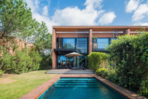 a house with a swimming pool in front of a house at Tróia Resort Beach Villa in Troia