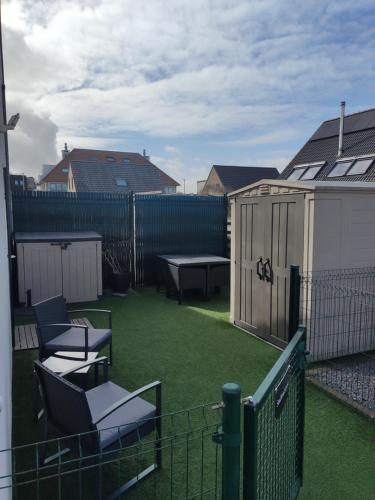 a backyard with chairs and a table and a fence at SeaBreak4you in Bredene