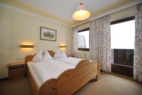 a bedroom with a wooden bed and a large window at Apparthotel Restaurant Steiners in Eben im Pongau