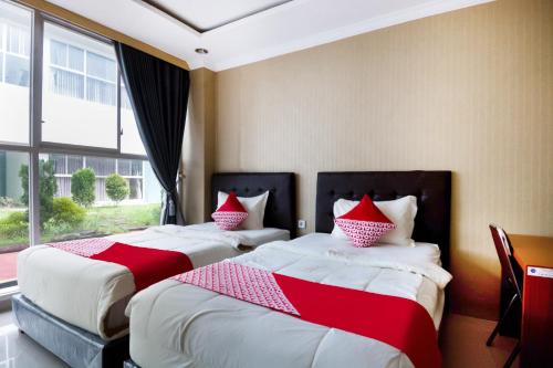 duas camas num quarto de hotel com almofadas vermelhas e brancas em Super OYO Collection O 3431 Hotel Alpha Bandara em Palimbão