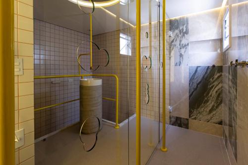a bathroom with yellow poles and a shower stall at Nuu Motel in São Paulo