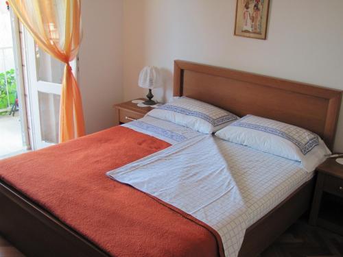 a bedroom with a bed with a orange blanket and a window at Guesthouse Marija in Cavtat
