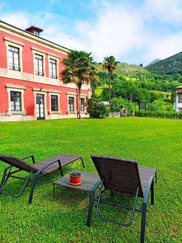 two chairs and a table in front of a building at La Venta de Miyares - Casa de Indianos in Piloña