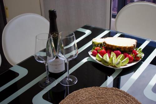 LUXURY Residence Gemelos 26 في بنيدورم: طاولة مع طبق من الفاكهة وكؤوس النبيذ