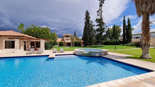 門多薩的住宿－Casa Agostino - Luxury wine and hotel in Bodega Agostino，一个带椅子的庭院和房子的游泳池