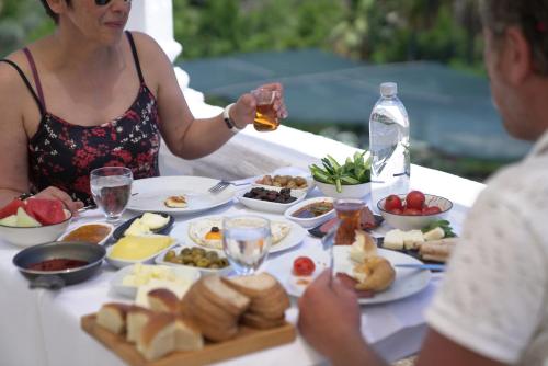 a woman sitting at a table with a plate of food at ASPAT HOTEL BODRUM - Beach&Restaurant in Bodrum City