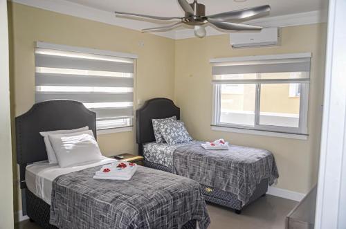 a bedroom with two beds and a ceiling fan at Beach Holidays at Marina Villa in Saint Annʼs Bay