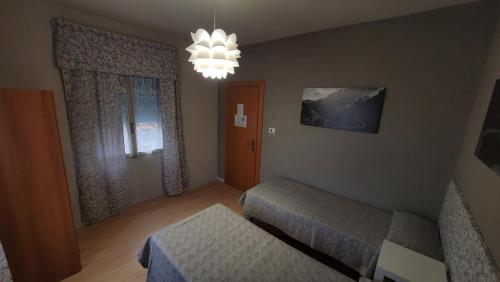 a small bedroom with two beds and a chandelier at Albergo Valentini in Baceno