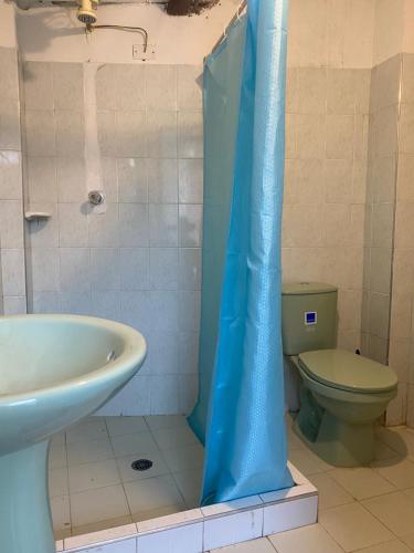 a bathroom with a toilet and a blue shower curtain at Cabaña con excelente ubicación y zona verde. in Iza