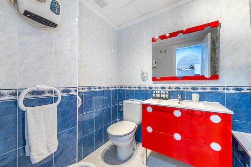 a blue and white bathroom with a toilet and a red cabinet at Puerto Pinar Luxe in Guardamar del Segura
