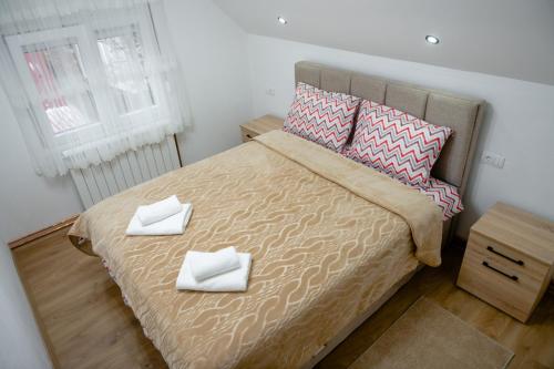 a bedroom with a bed with two white towels on it at Golden House in Kolašin