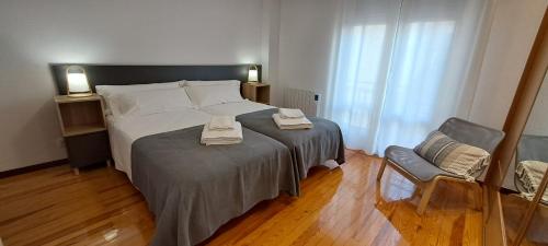 1 dormitorio con 1 cama grande y 1 silla en Erdizka, céntrico apartamento turístico con la mejor vista Plaza de los Fueros, en Estella